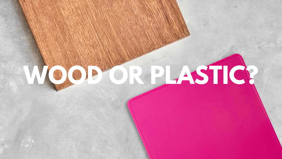 2 cutting boards on a gray surface, one pink and one wood. The text reads: wood or plastic?